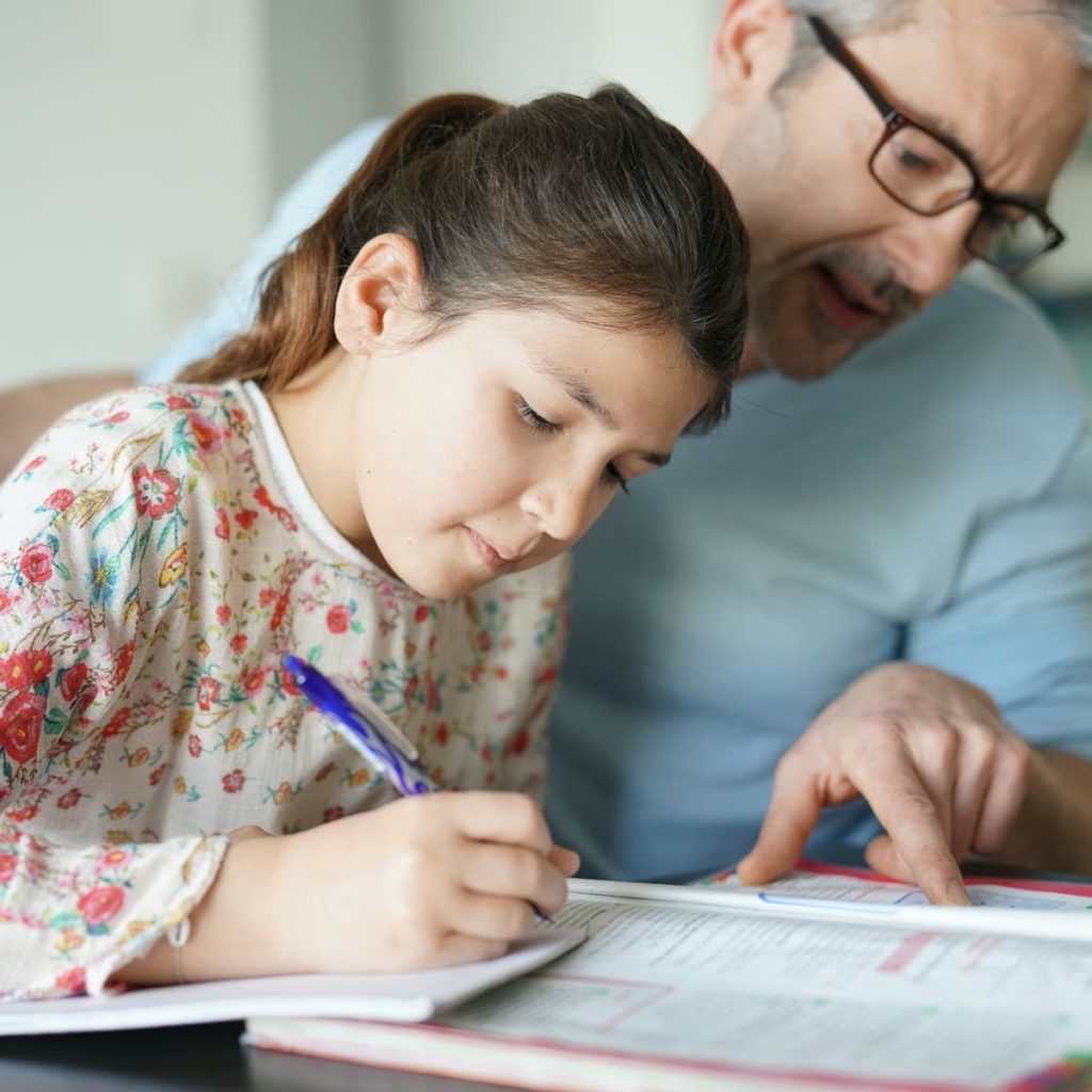 girl writing a word with her parents